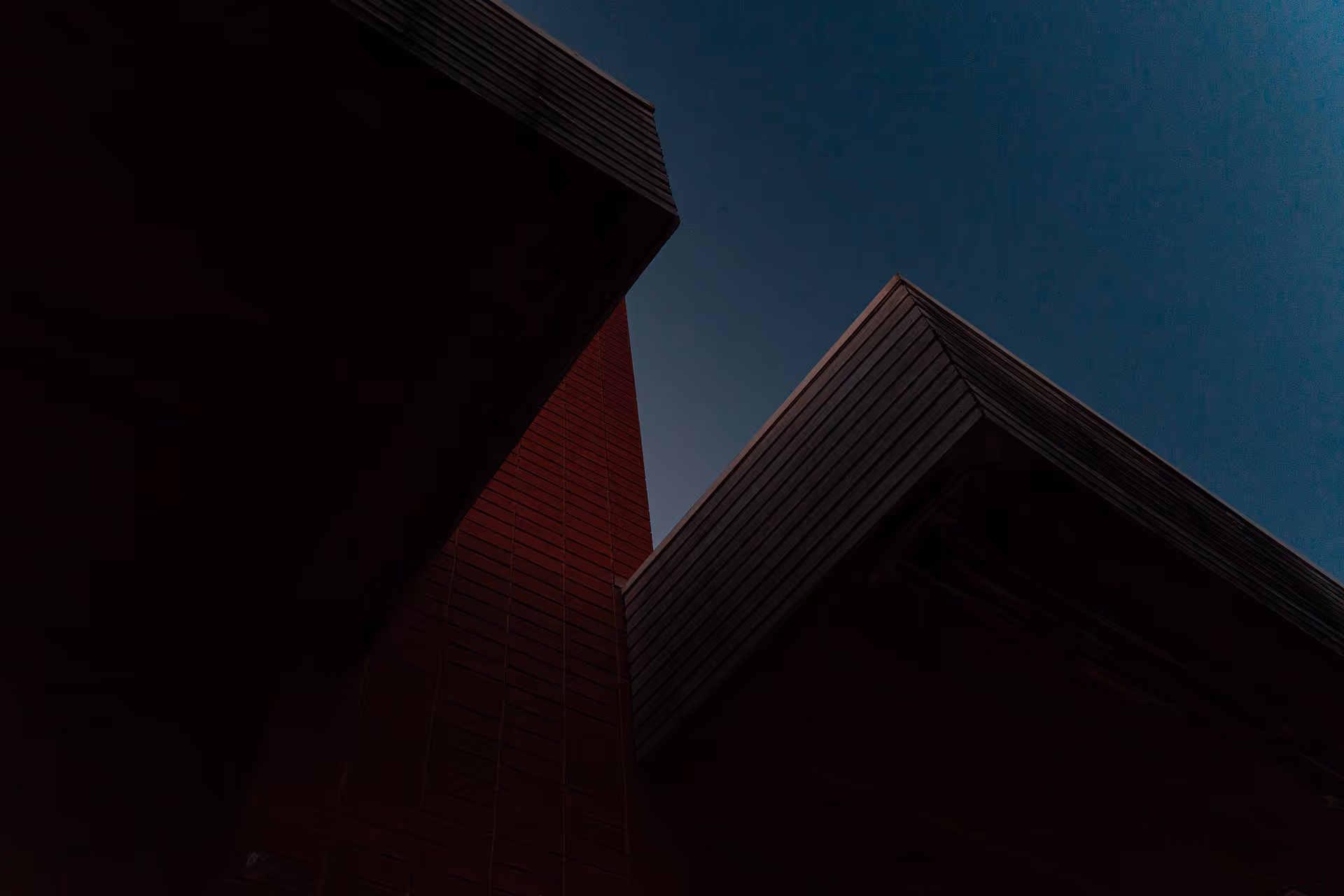 A red building stands against a clear blue sky, creating a vibrant contrast in the scene.